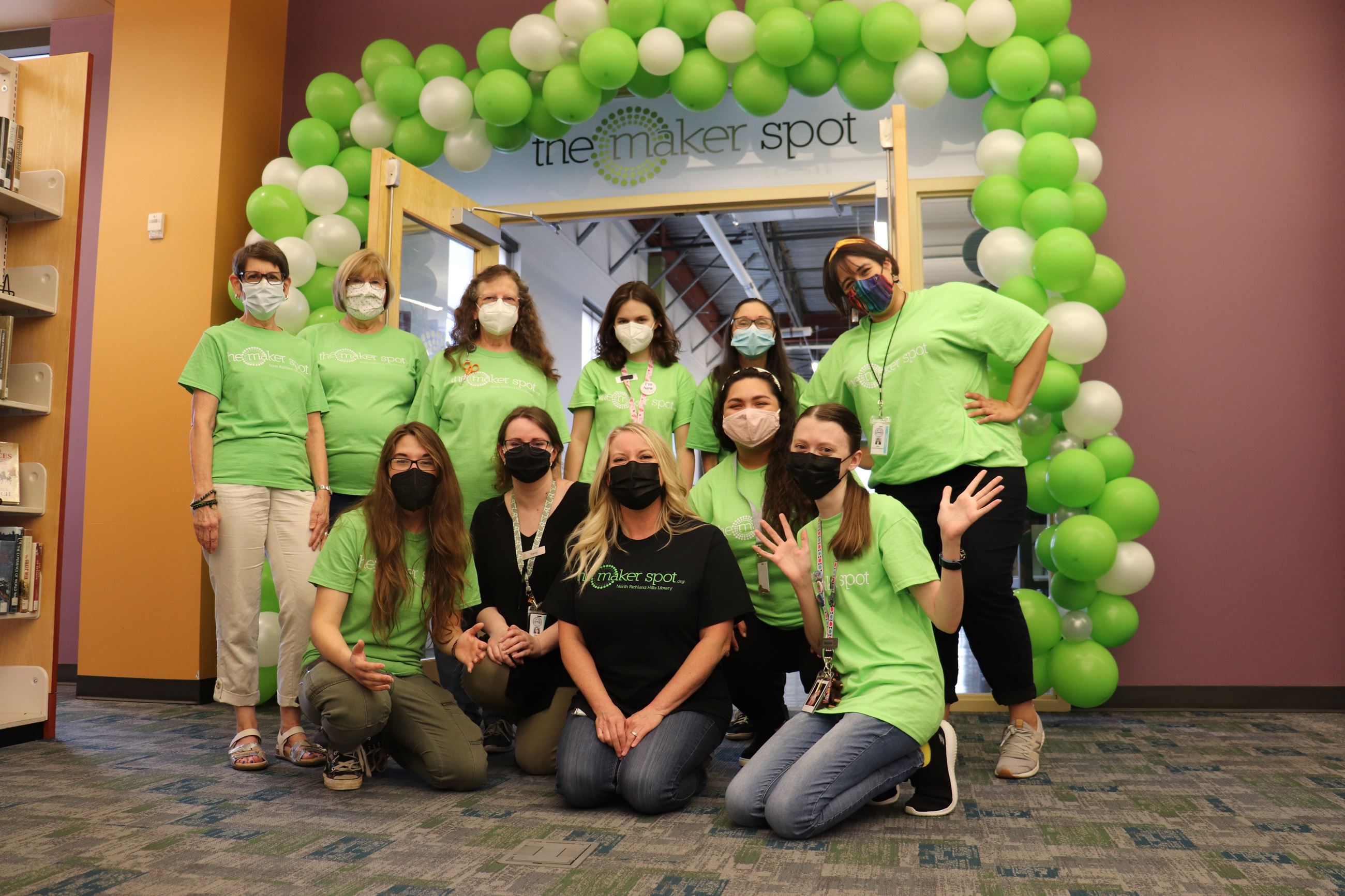 Library staff wearing green shirts standing in front of The Maker Spot with balloons