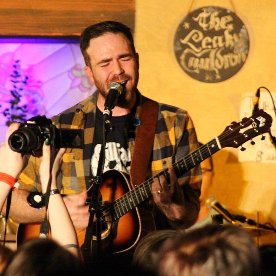 Man in flannel shirt singing with guitar