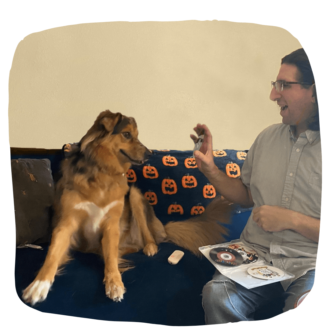 A man holding a dvd up to a dog